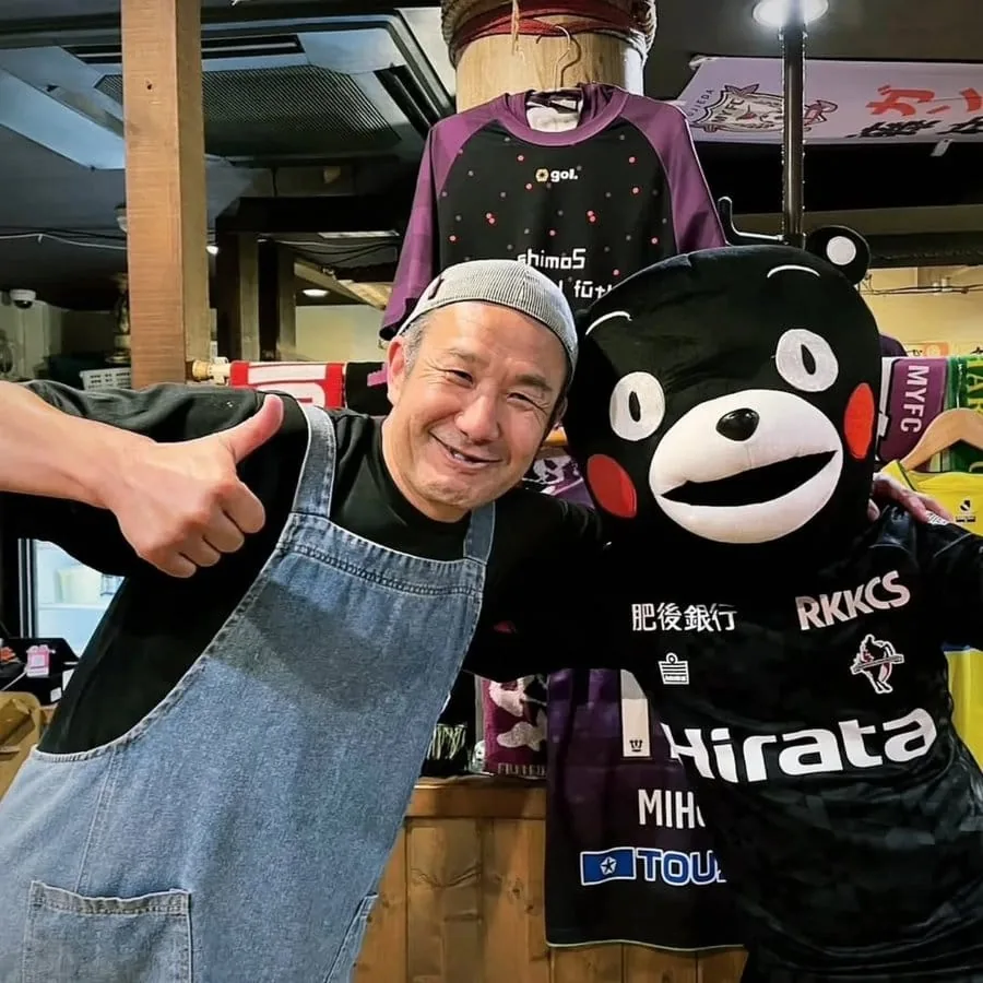 店内で親指を立てて笑う店主・渡部晋（すっくん）
